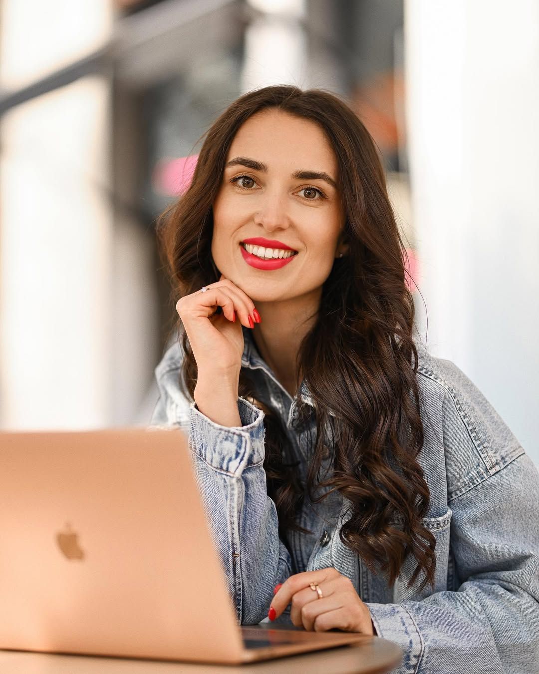 Confident remote worker smiling at the camera with her laptop at a cafe in Valencia. Professional branding portrait