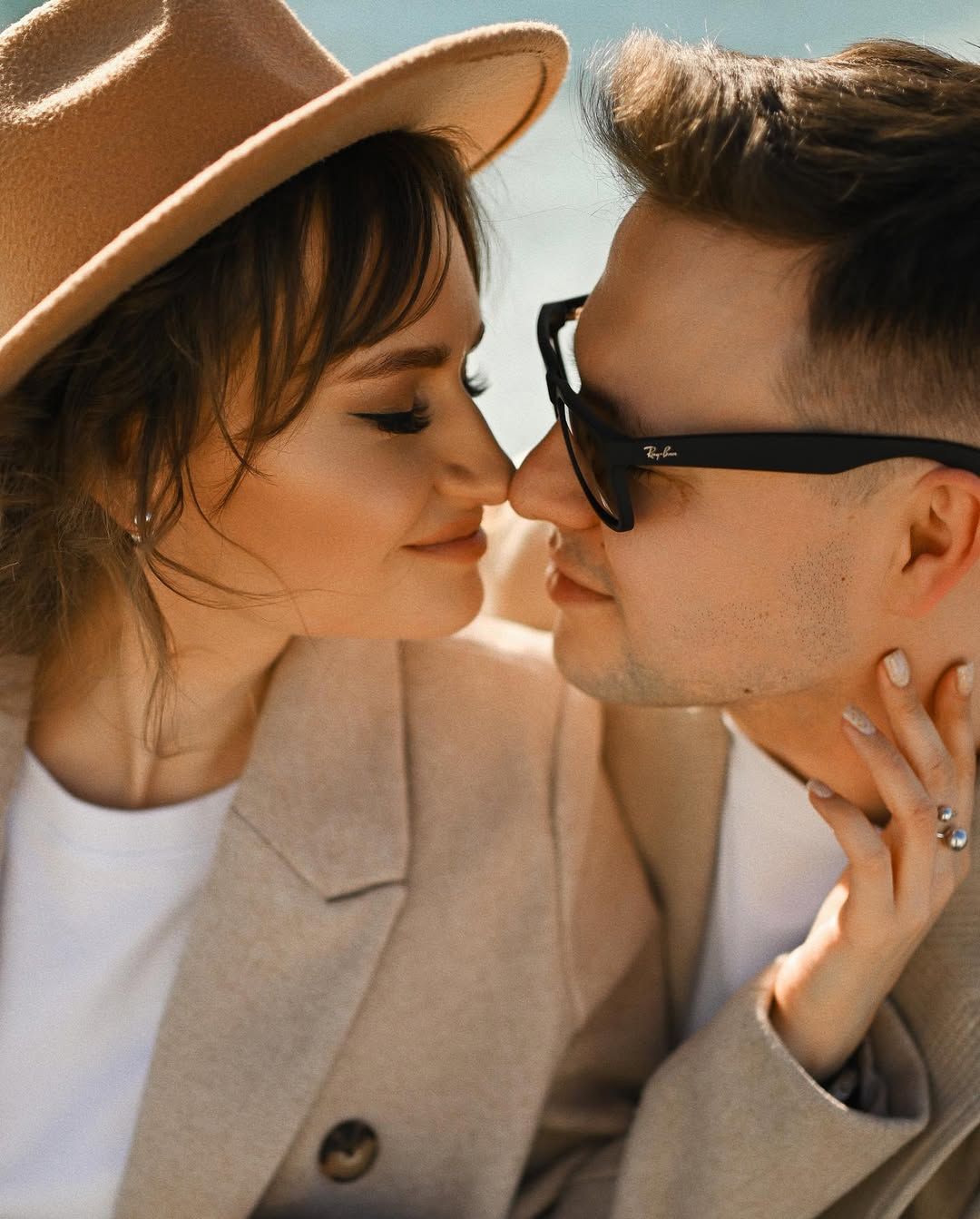 Close-up portrait of a woman in a brown hat looking at her partner during a sunny Valencia love story shoot.