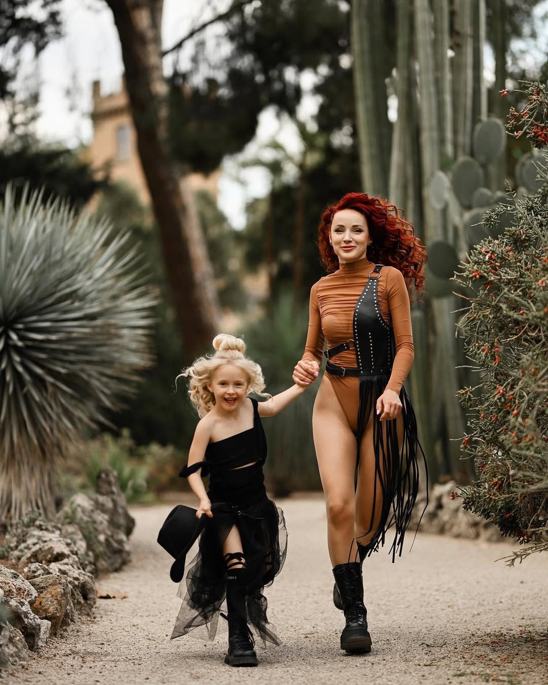 A mother and daughter holding hands while walking along a path in the Botanical Garden of Valencia.