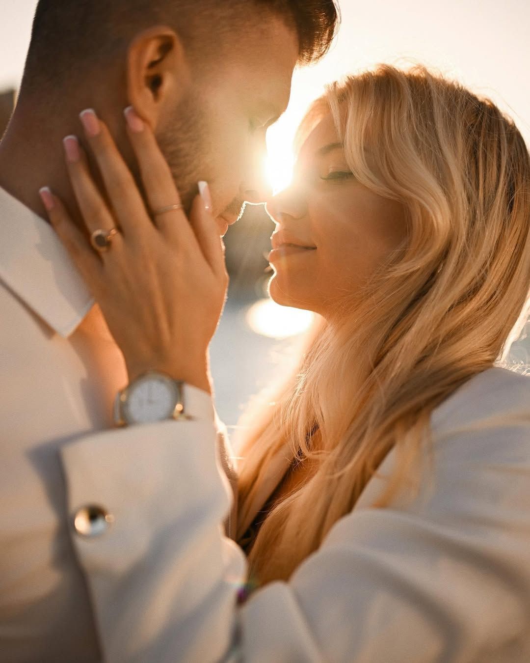 Close-up romantic portrait of a couple with a beautiful sun flare shining between their faces during sunset