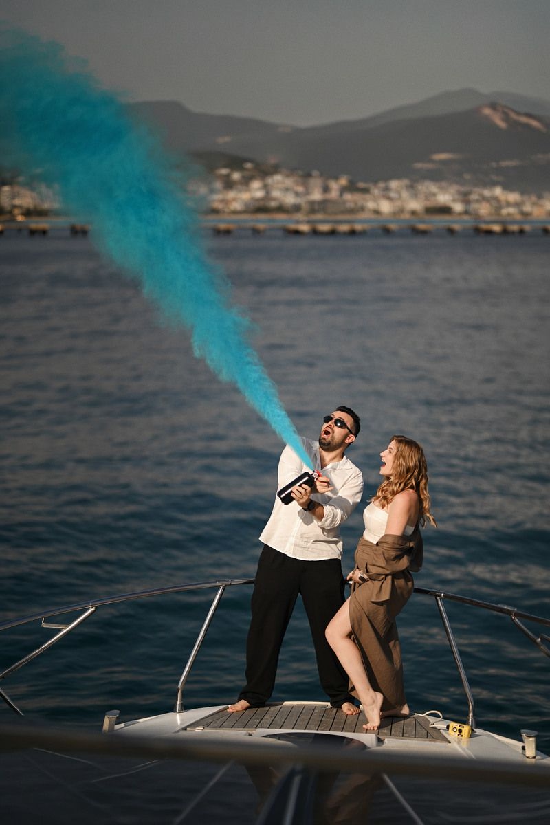 Couple firing a blue smoke cannon on a yacht in Valencia, revealing they are expecting a boy during their gender reveal.