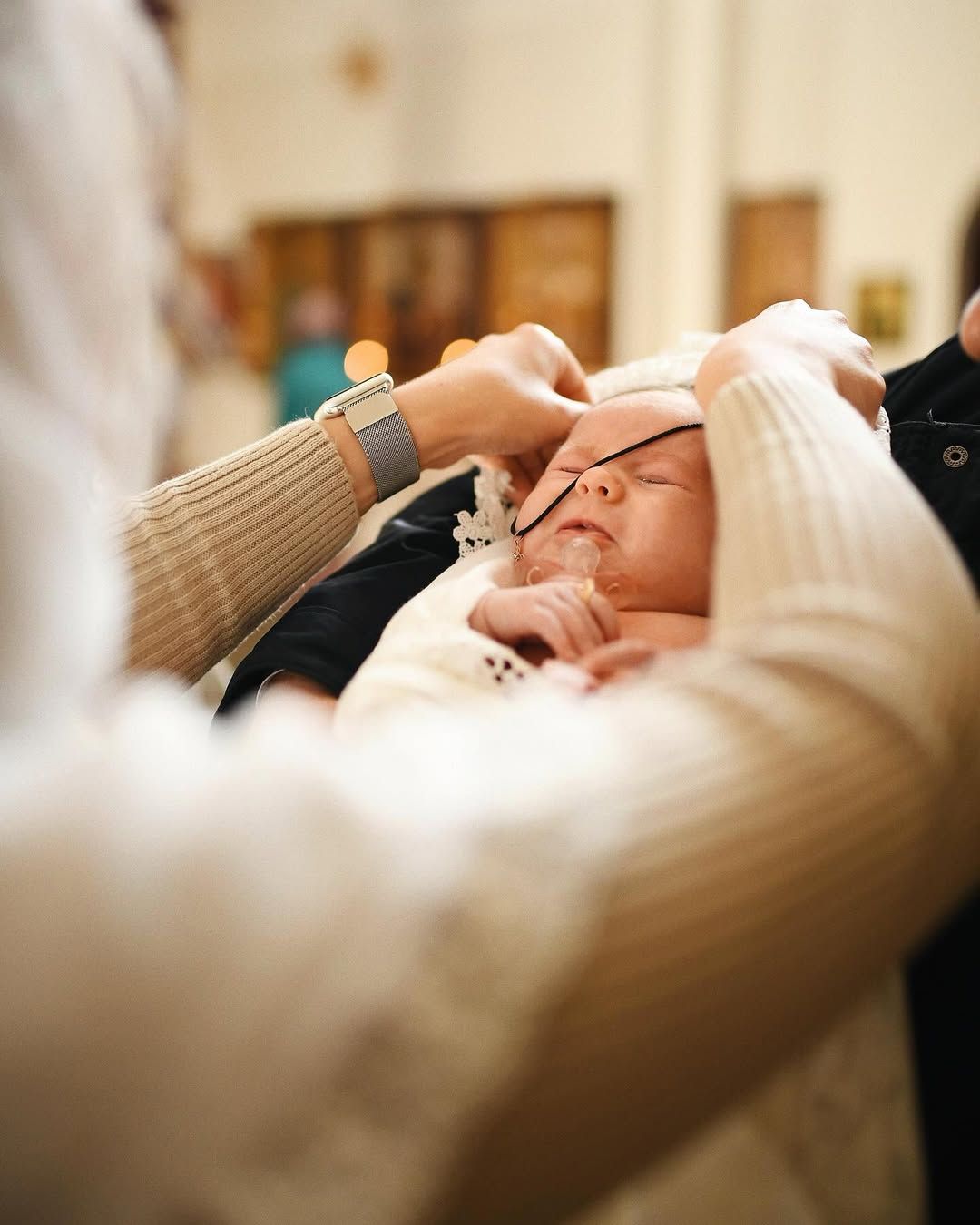 Close-up of placing a traditional cross necklace on a newborn baby during a christening ceremony in Valencia