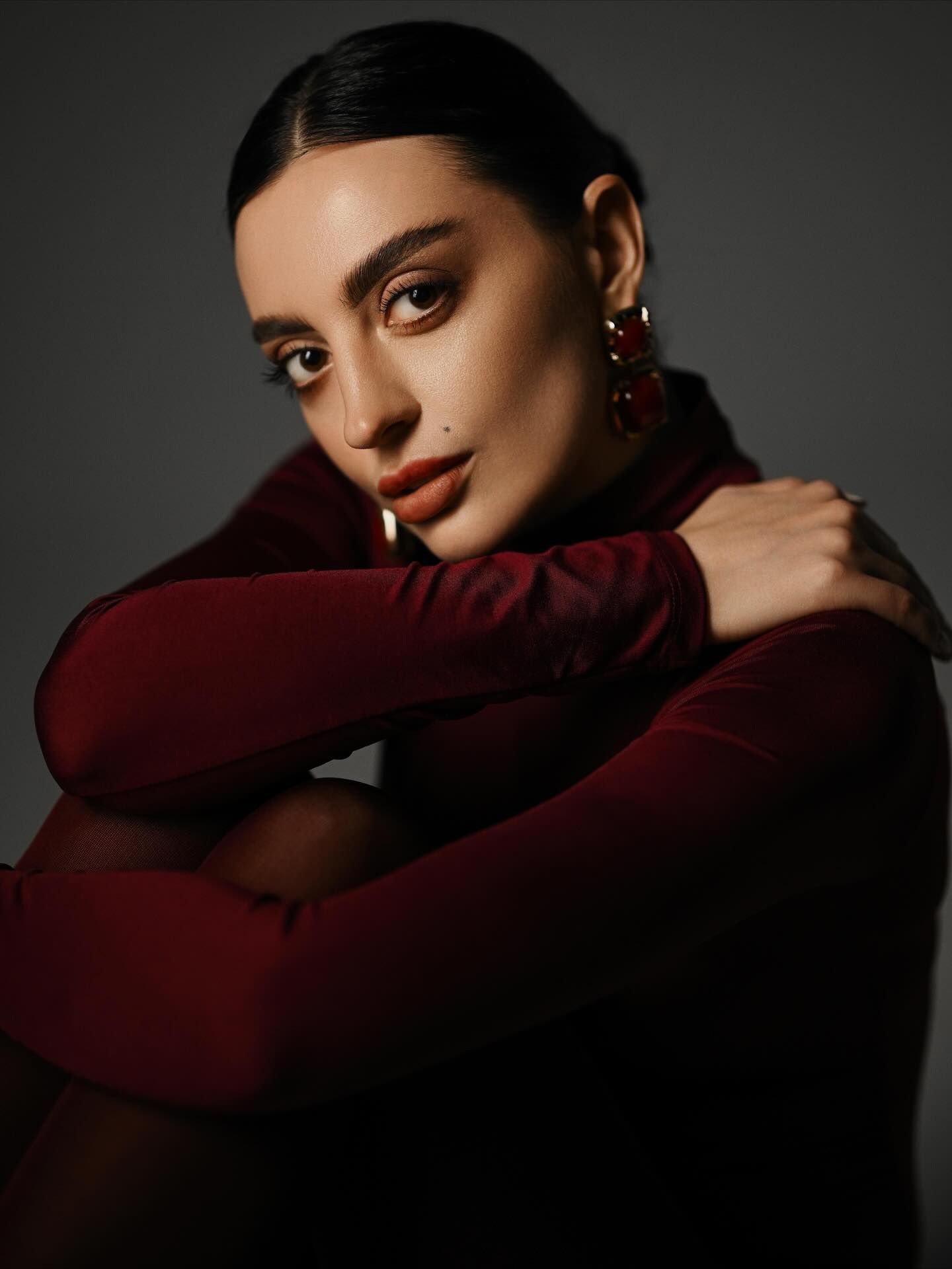 High-end editorial fashion portrait of a model in a burgundy dress, showcasing premium lifestyle photography services in Valencia.