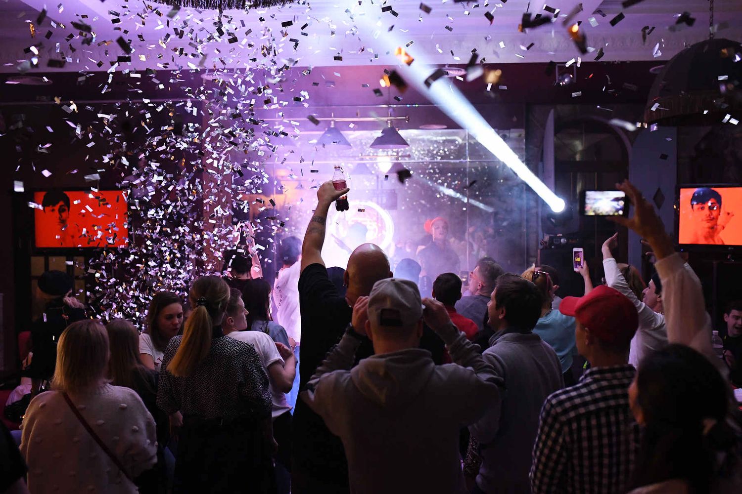High-energy corporate event reportage showcasing a crowd celebrating under falling silver confetti at a private party.