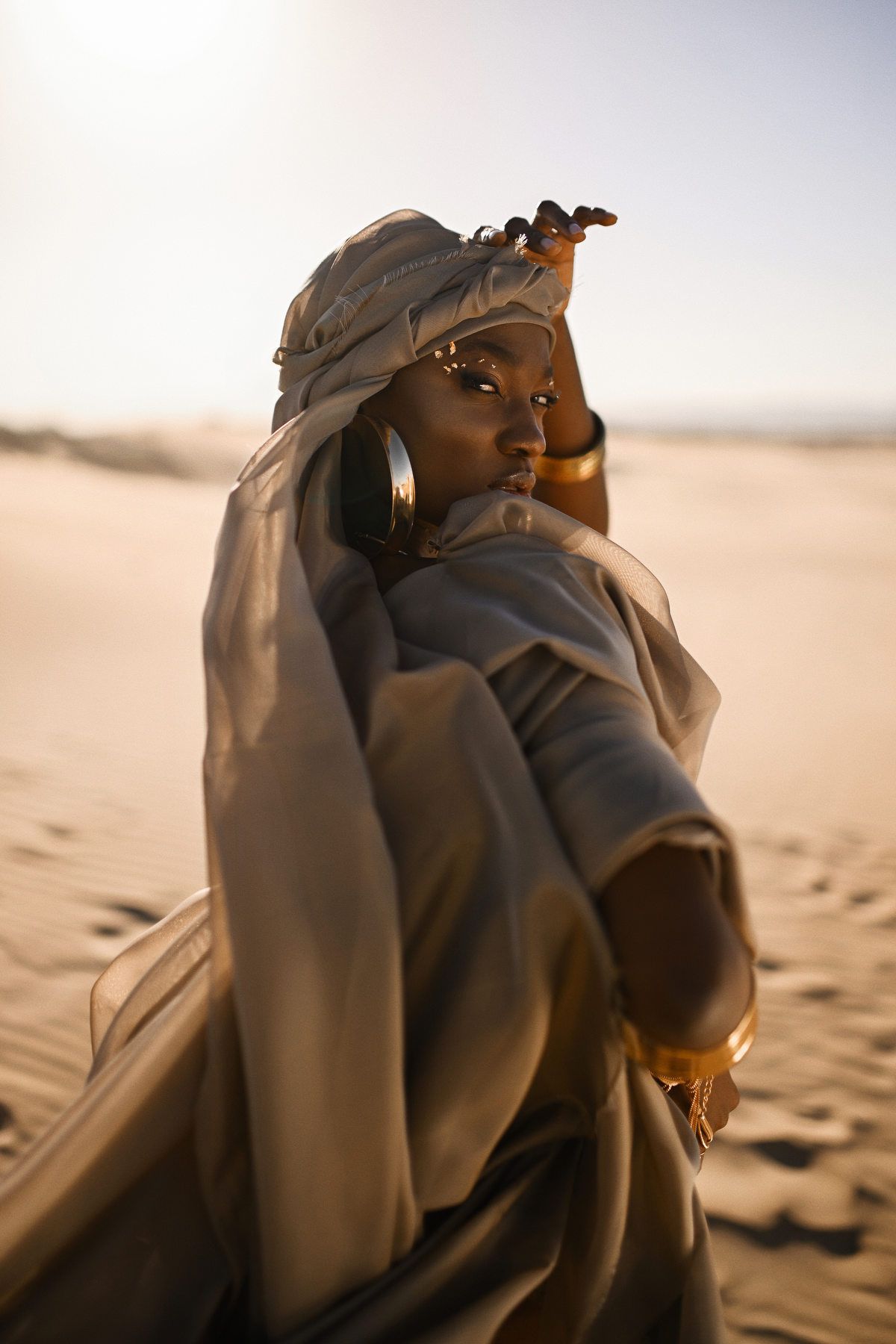 Striking editorial model test portrait showcasing high-fashion styling and creative lighting in a desert landscape.