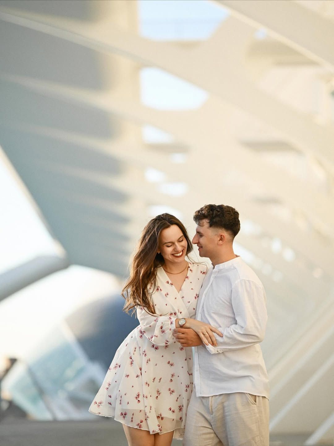 Candid portrait of a laughing young couple in elegant white outfits during their session at the City of Arts and Sciences