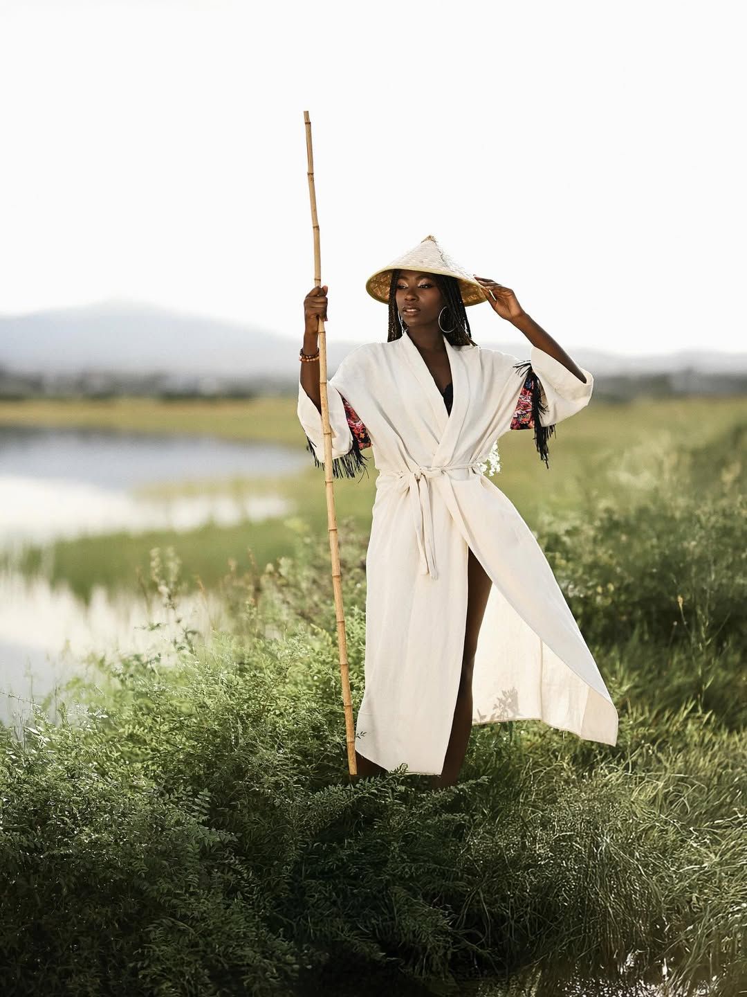Conceptual photoshoot in Albufera featuring professional makeup, braided hair, and an ethnic wardrobe with a bamboo pole