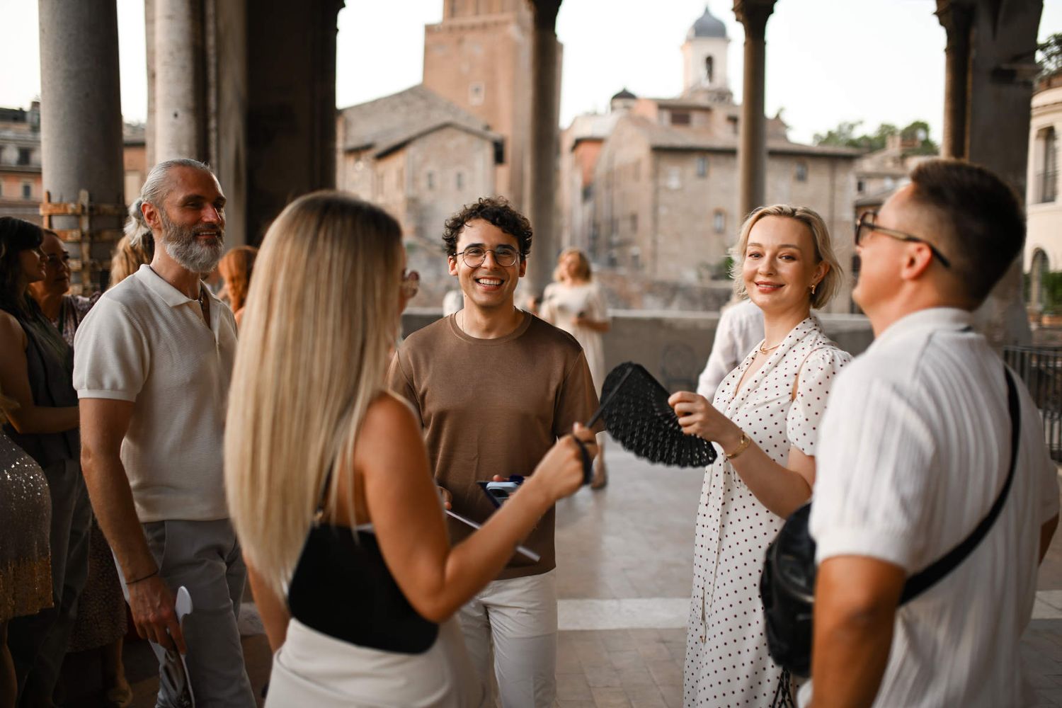 Guests talking and smiling during an upscale outdoor cocktail hour at a historic European venue.