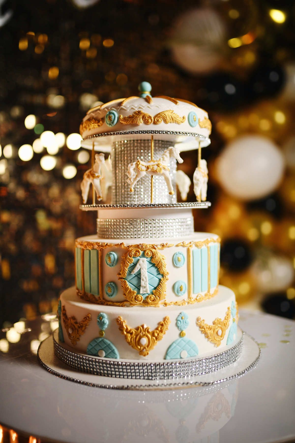 Close-up of a luxury multi-tier birthday cake designed as a carousel with white decorative horses and golden details.