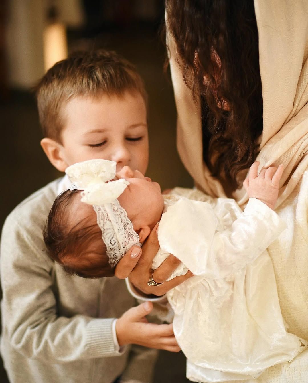 Older brother kissing his baby sister in a white gown during a beautiful christening ceremony in Valencia