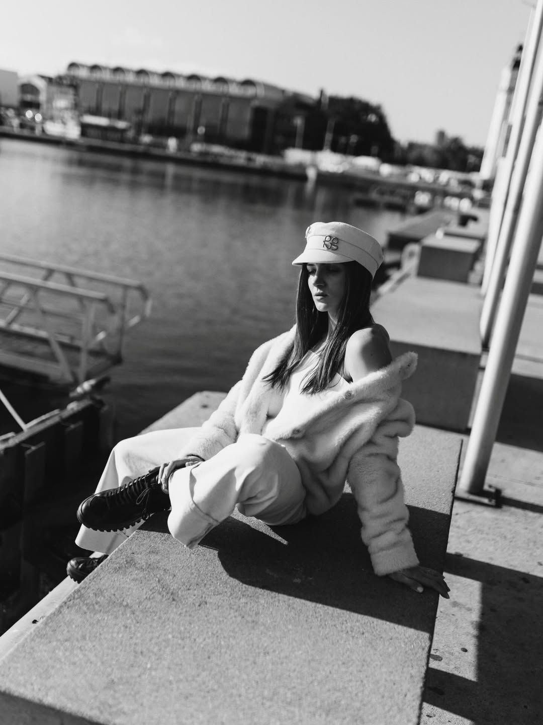 Black and white editorial portrait of a woman sitting on the concrete canal edge in Valencia Marina