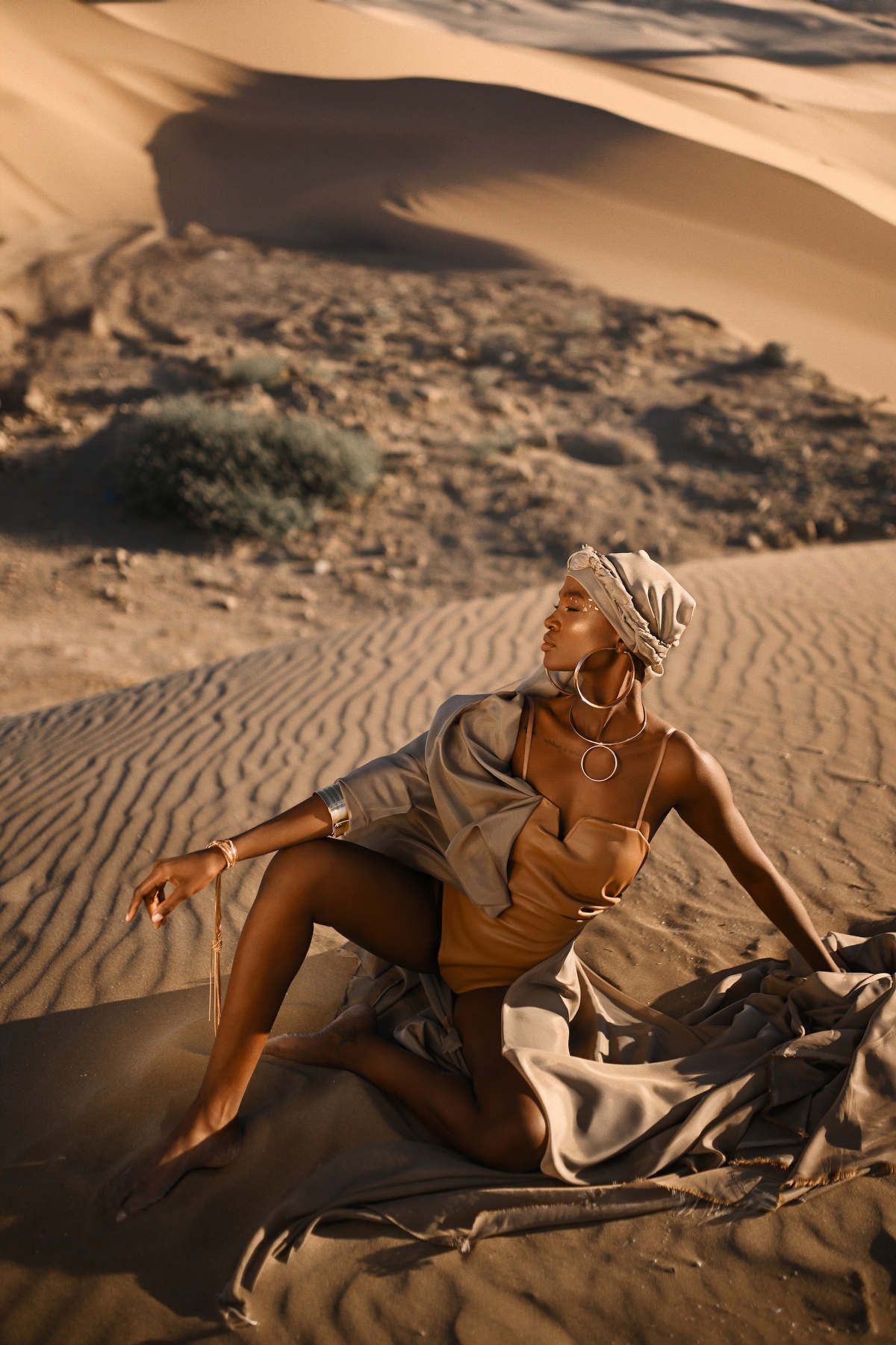 ditorial lookbook photography showing a model posing elegantly on sand dunes for a high-end clothing brand campaign.