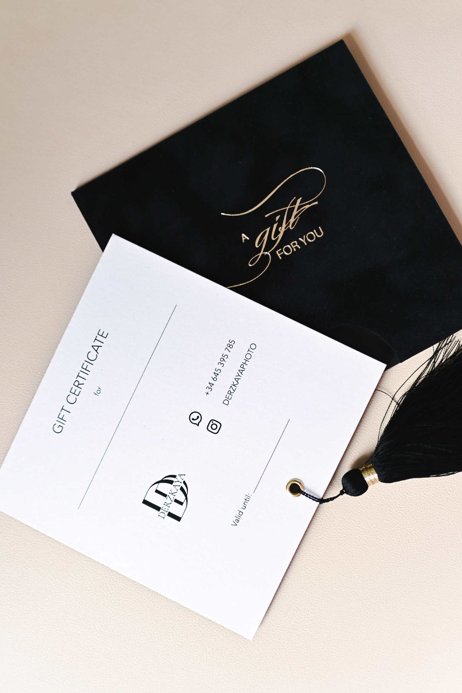 Elegant black photoshoot gift vouchers in Valencia with gold foil typography and decorative tassels.