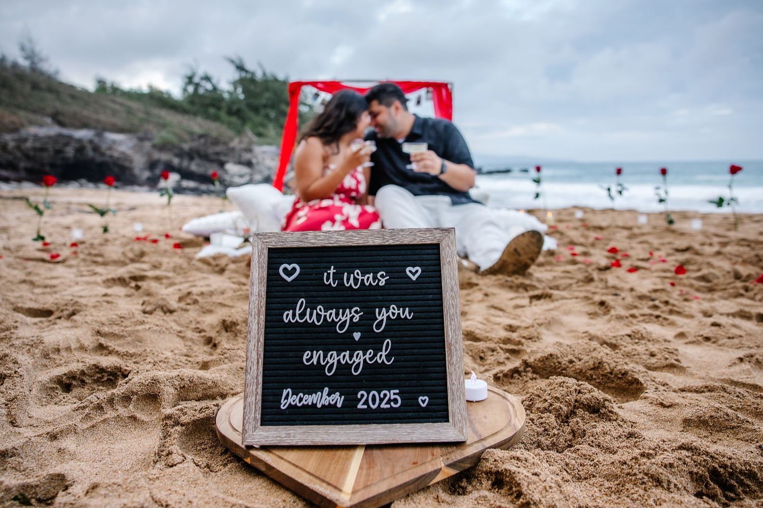 Engagement photo session on a sandy beach with small chalkboard signs and romantic poses at sunset.