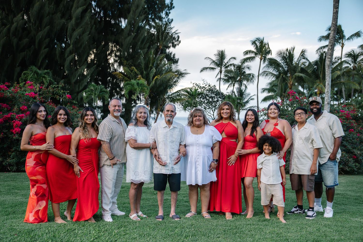 Wedding party poses on a lush tropical lawn with palm trees in the background.