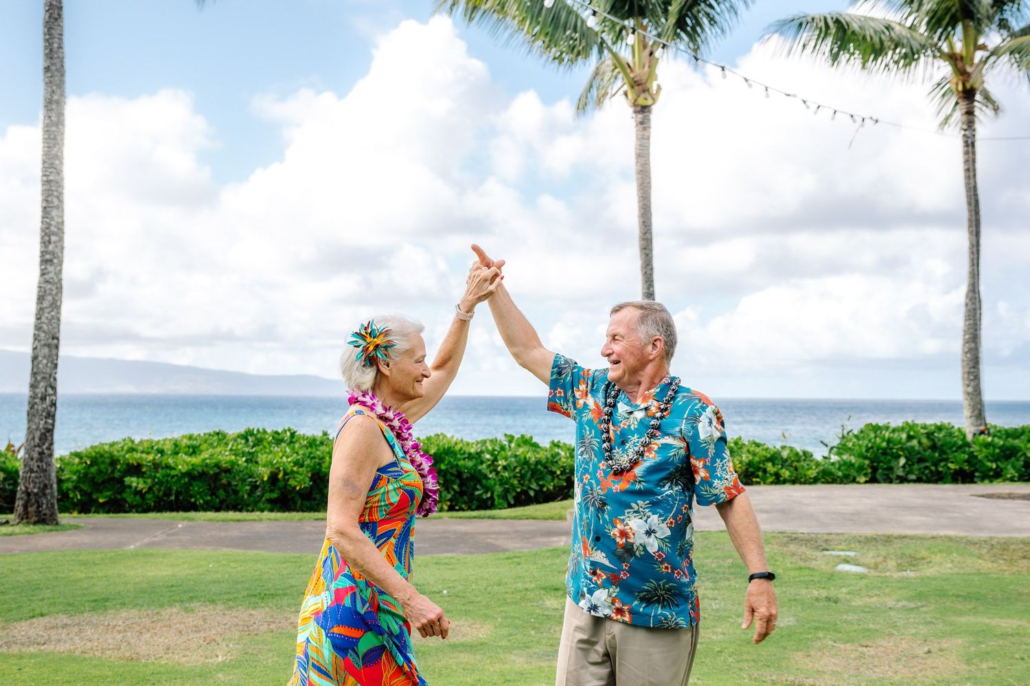 Family wearing coordinated blue and white outfits poses playfully on a tropical beach with palm trees.