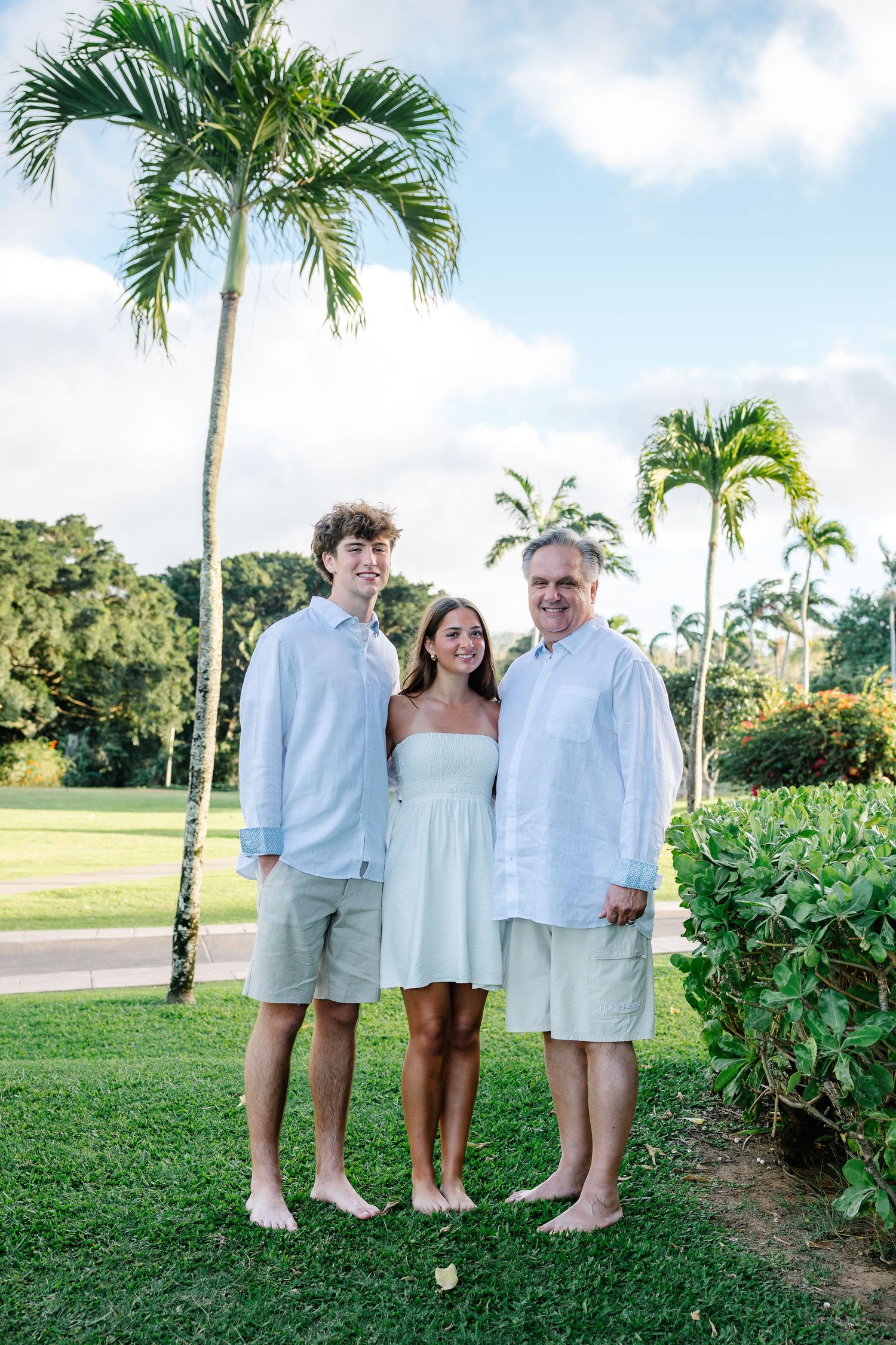 Family portrait session in white clothing against a tropical landscape with palm trees.