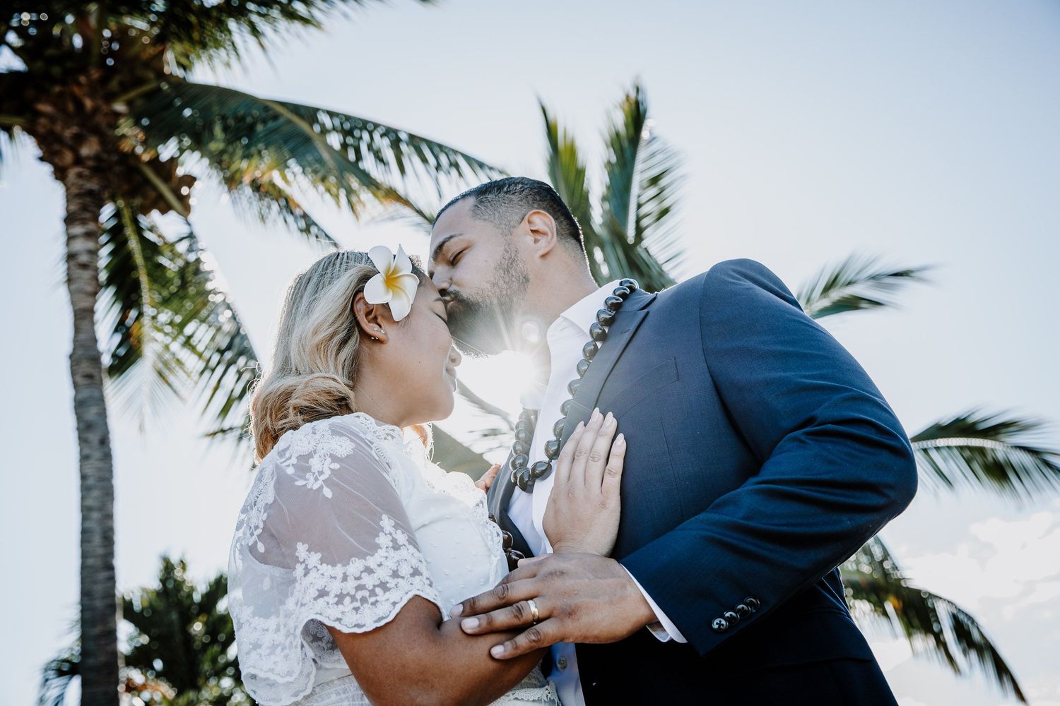 Wedding portraits with swaying palm trees and blue sky in tropical setting.