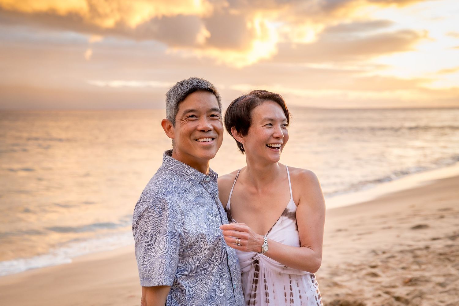 Couple shares intimate moment during sunset beach photo session in Hawaii.