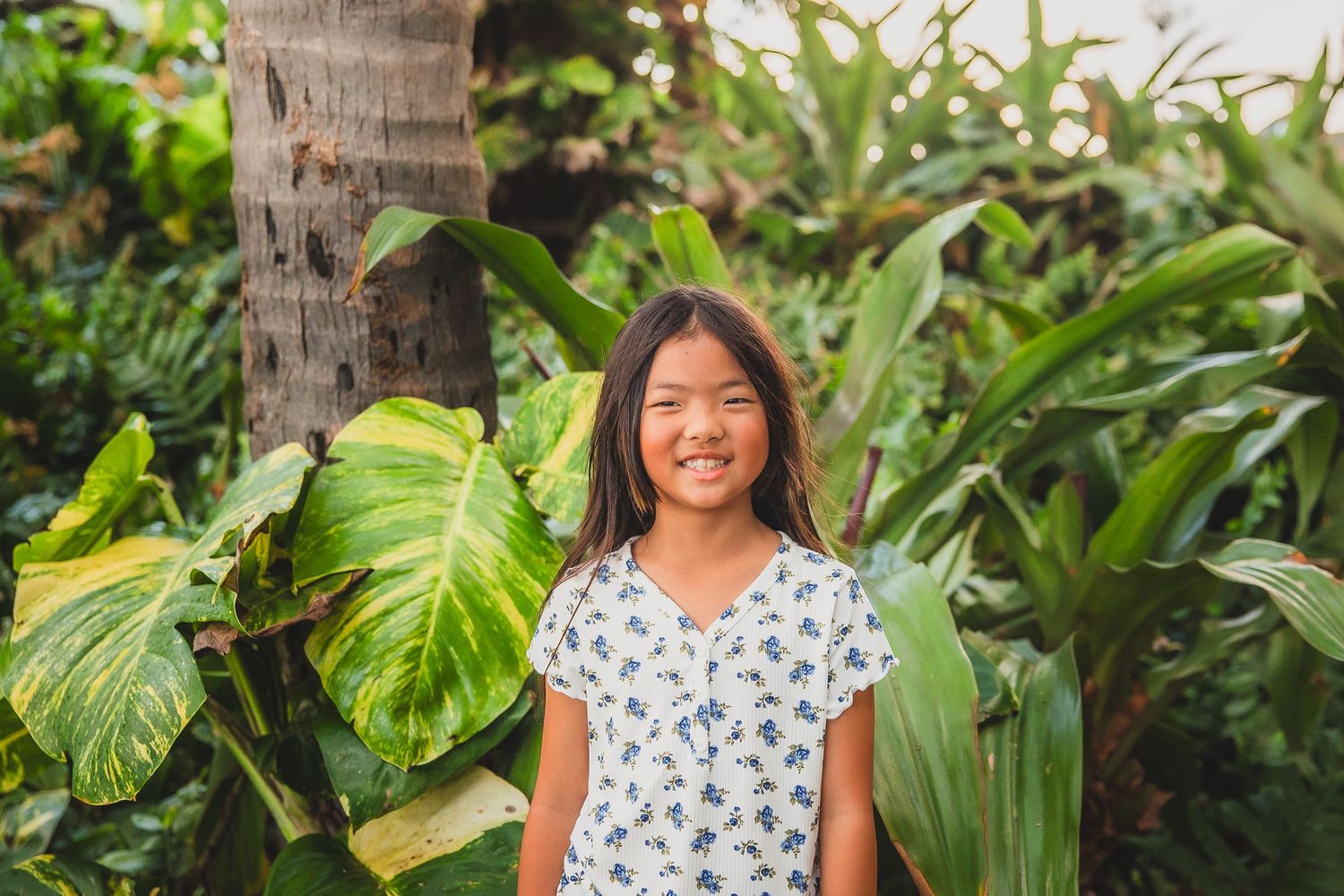 Portrait session in a lush tropical garden with palm fronds and greenery.