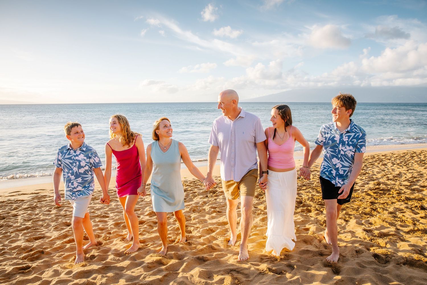 Group photo on a golden sand beach with waves and mountains in the distance.