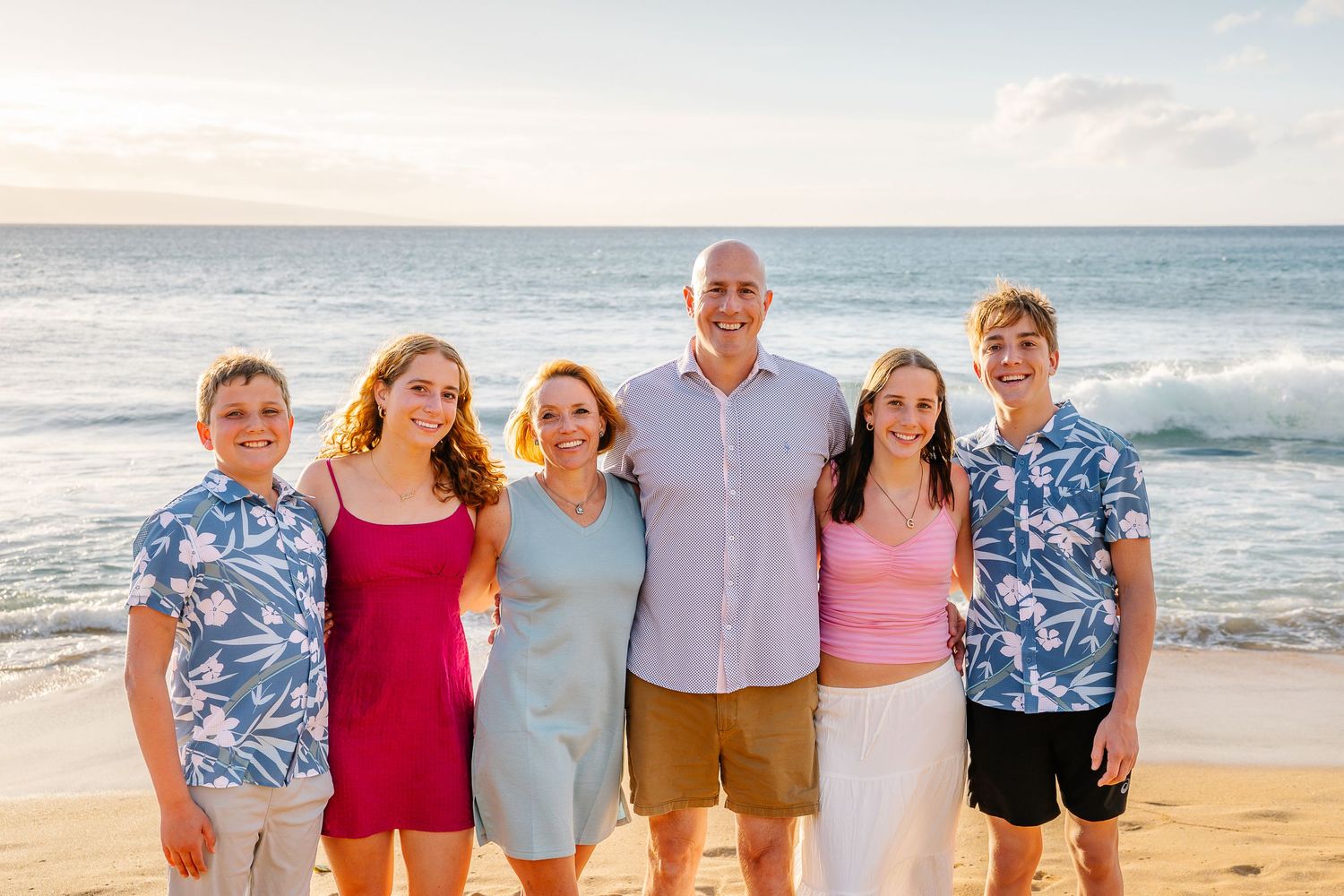 People gathered on a tropical beach wearing coordinated blue and pink outfits.