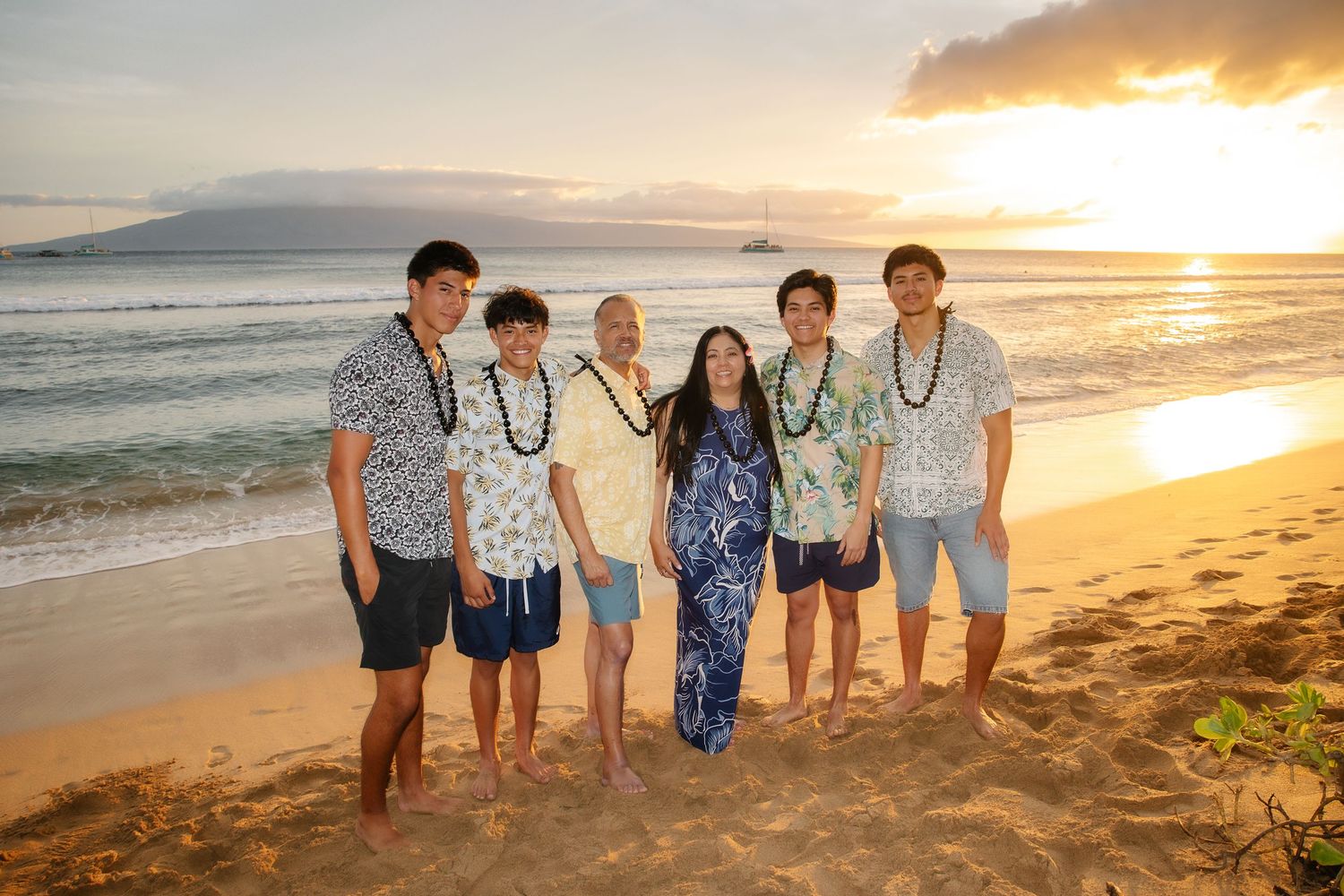 A group of people standing together on a beach at sunset with golden light illuminating the shoreline.