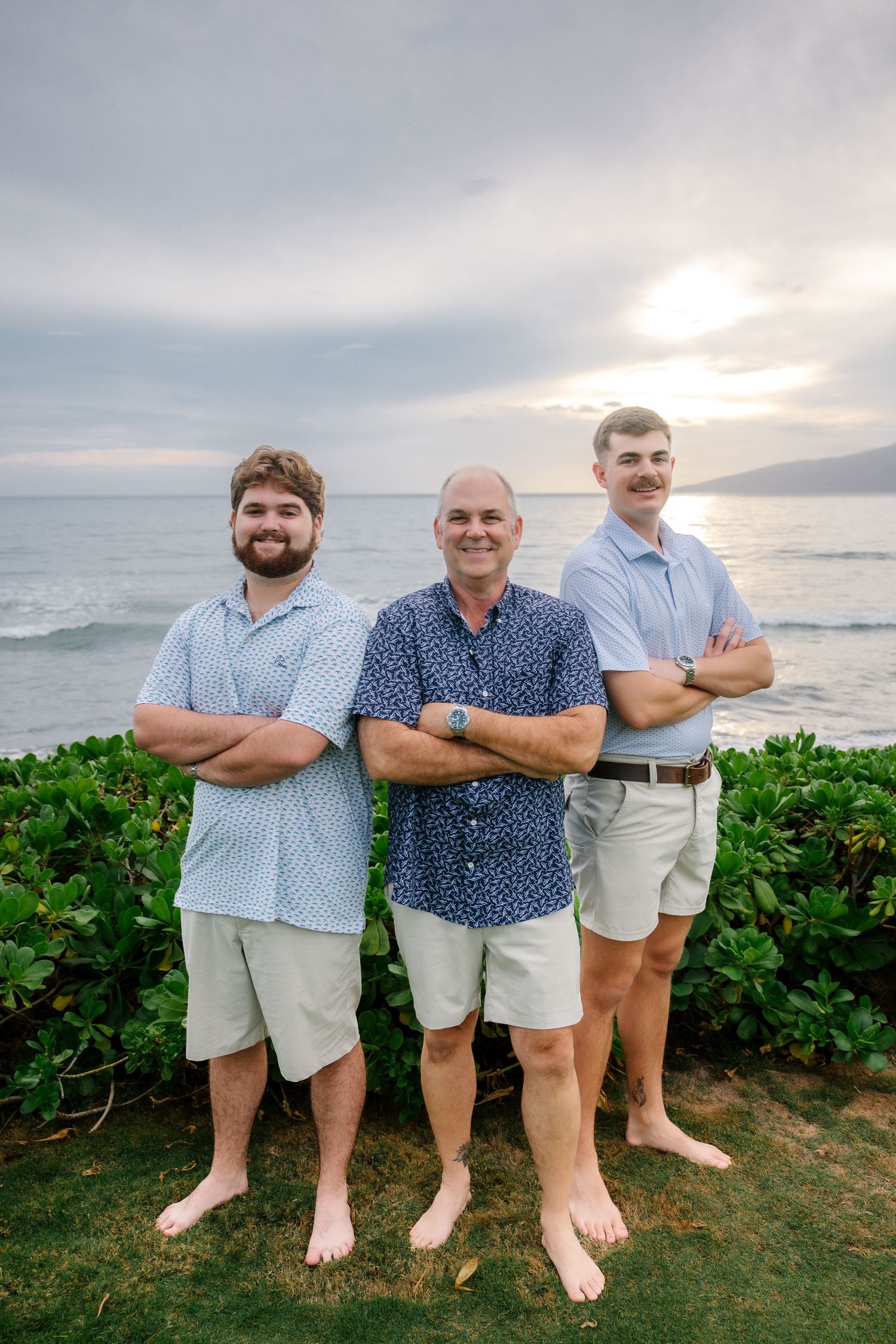 Group of men in coordinated blue and white outfits posing at oceanfront location.
