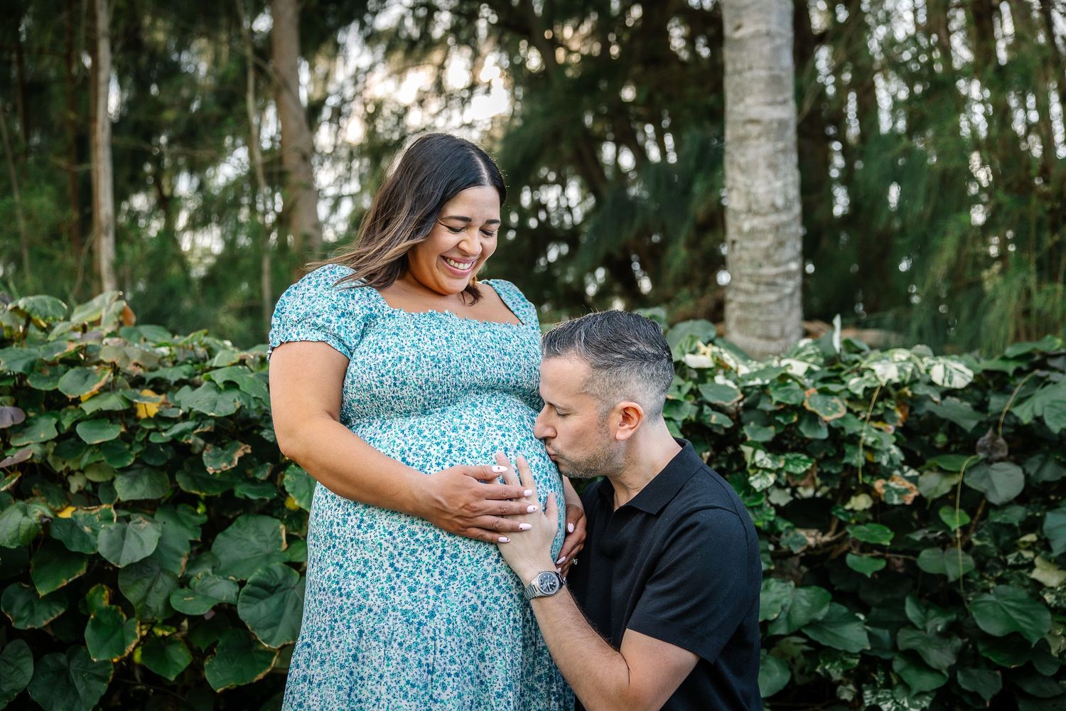 Intimate maternity photo session in a wooded setting with natural lighting and greenery.