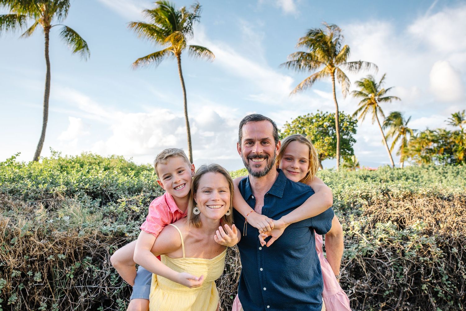 Extended family gathering for photos in tropical beach setting with palm trees.