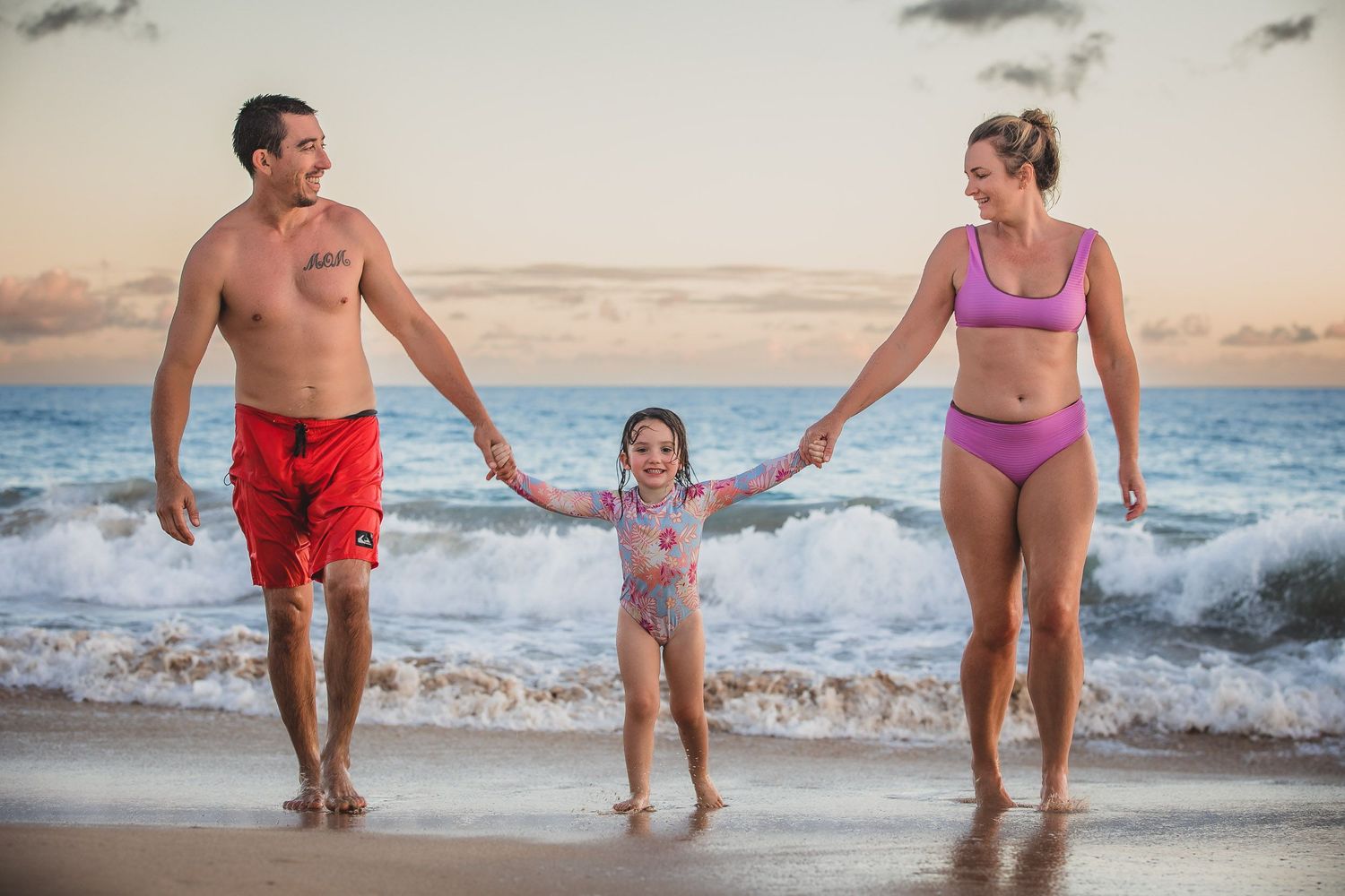 People playing and splashing together in ocean waves at sunset.