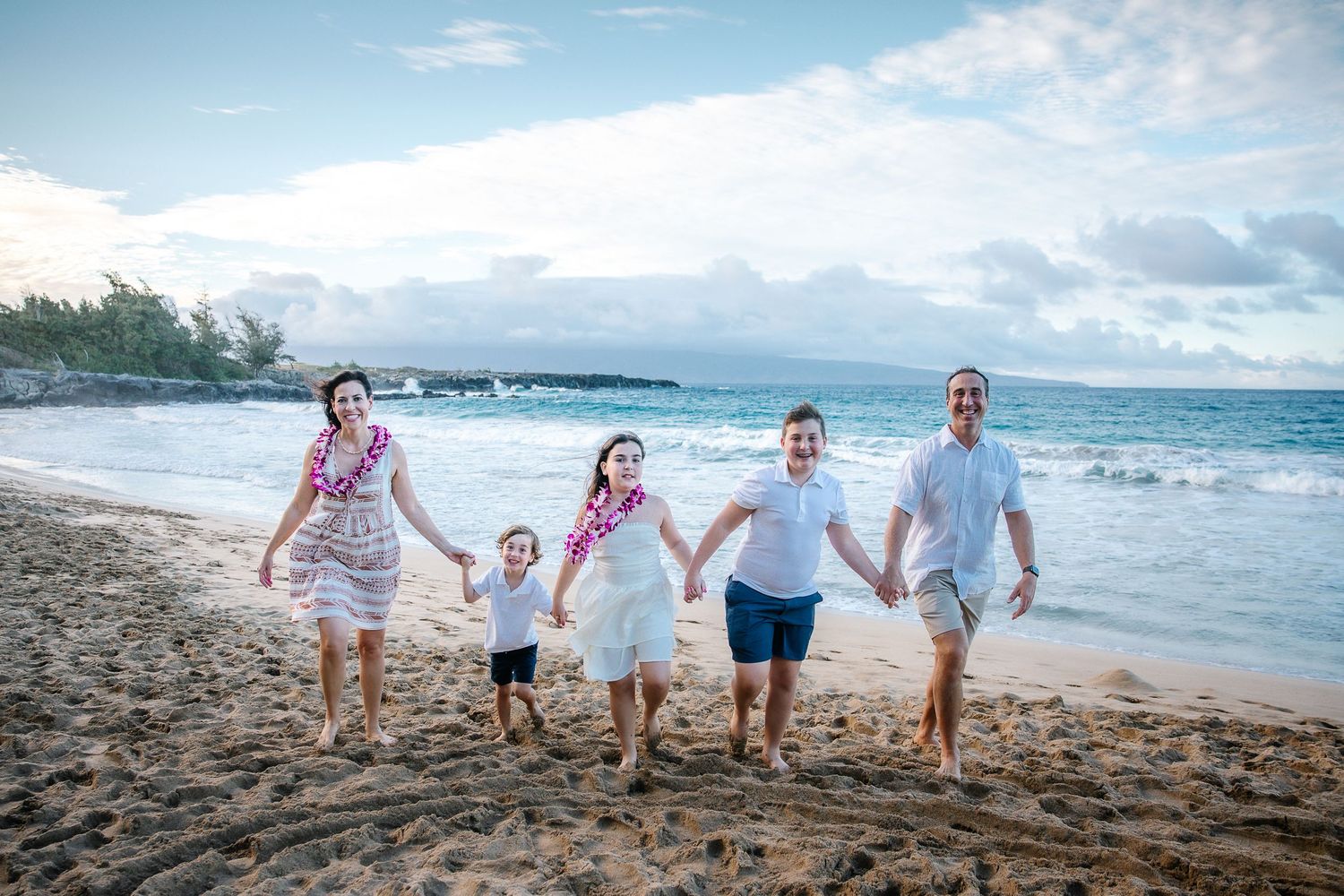 Happy family running and holding hands together on a beautiful Hawaiian beach.