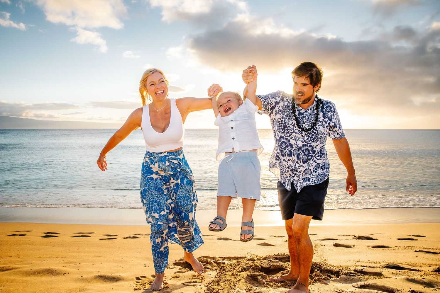 Group of people walking and playing together on a sandy beach at sunset with ocean waves in the background.