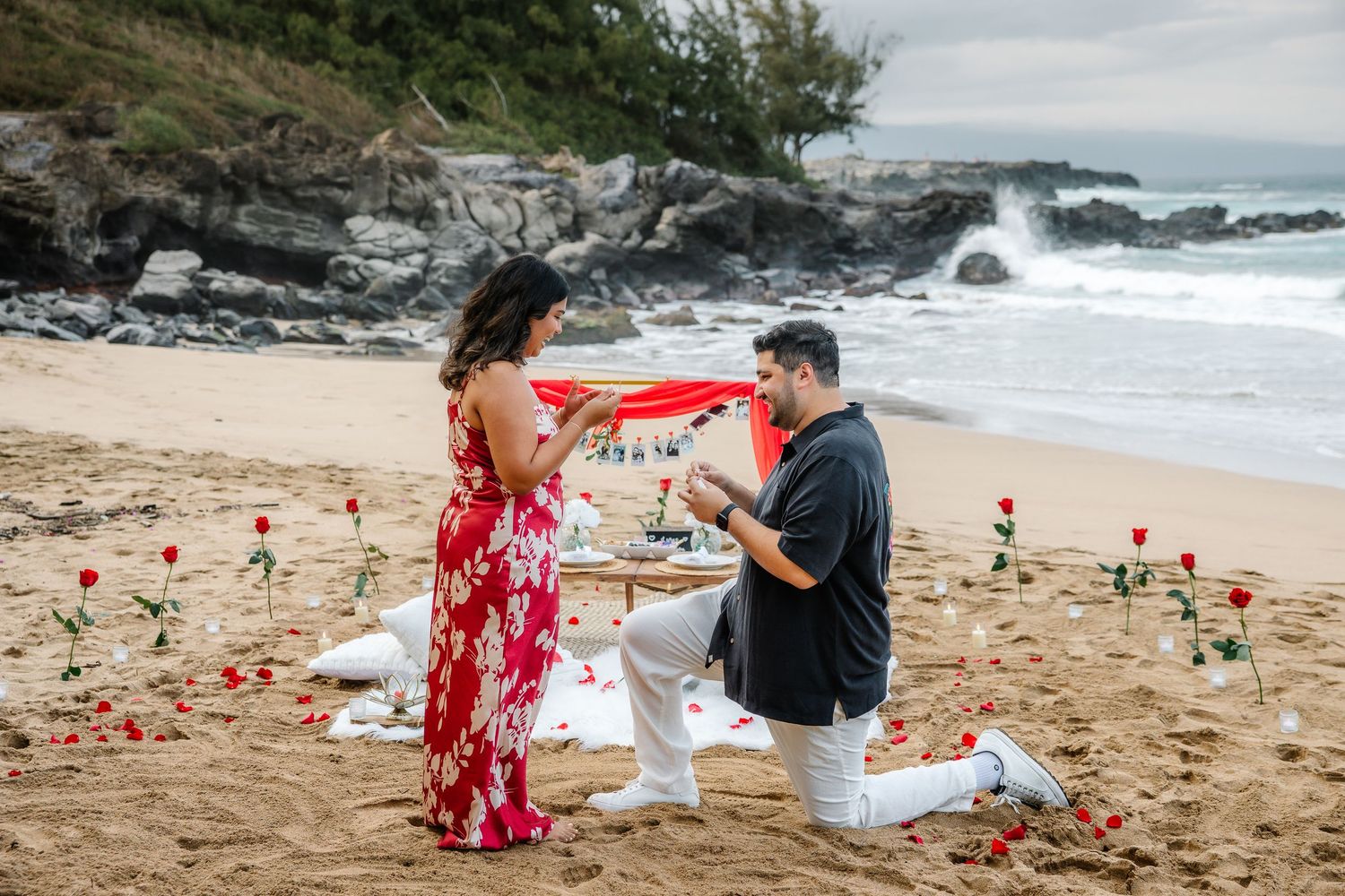 A romantic beach scene with scattered rose petals and coastal rocks at sunset.