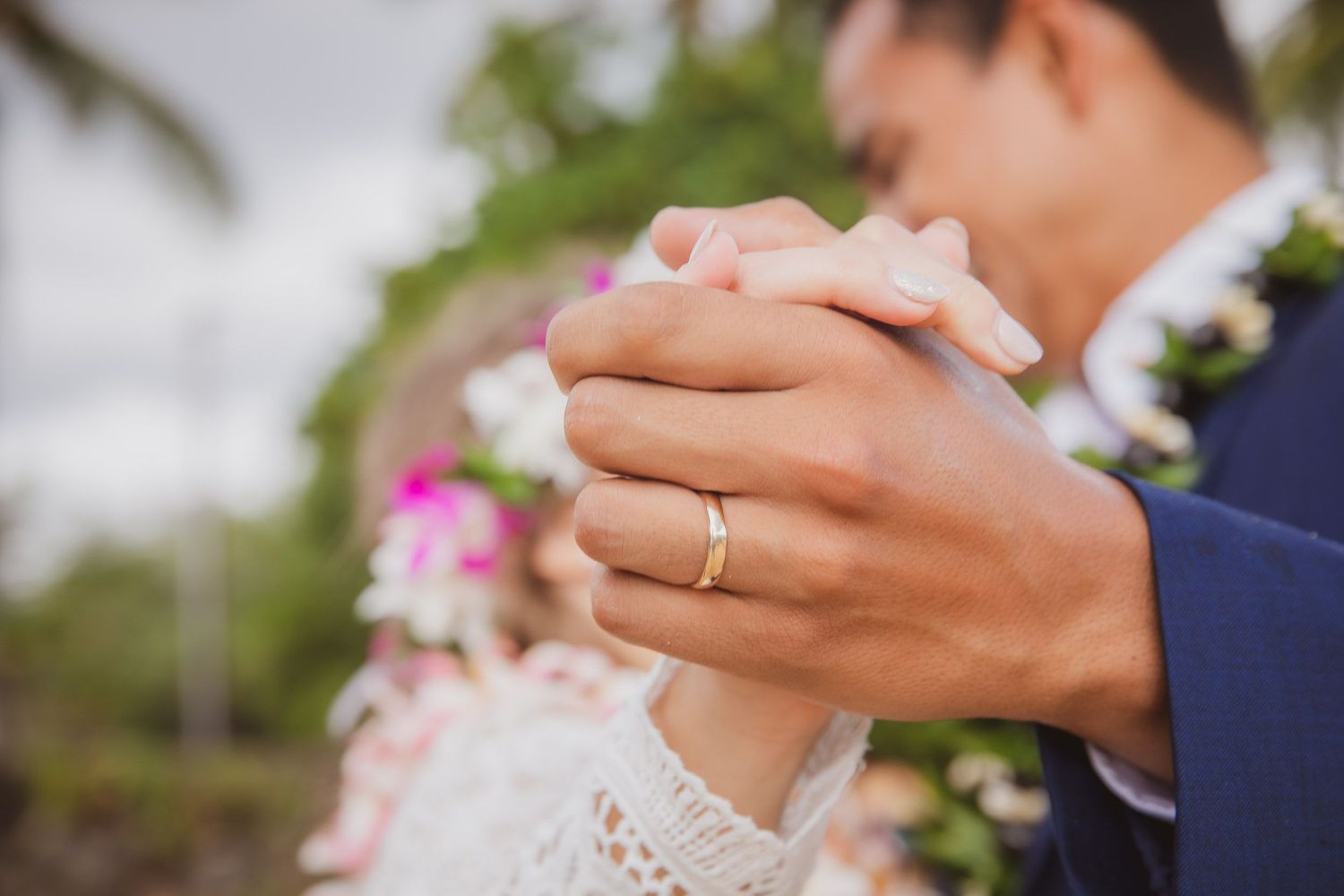 Close-up of hands with wedding rings during an intimate ceremony moment.