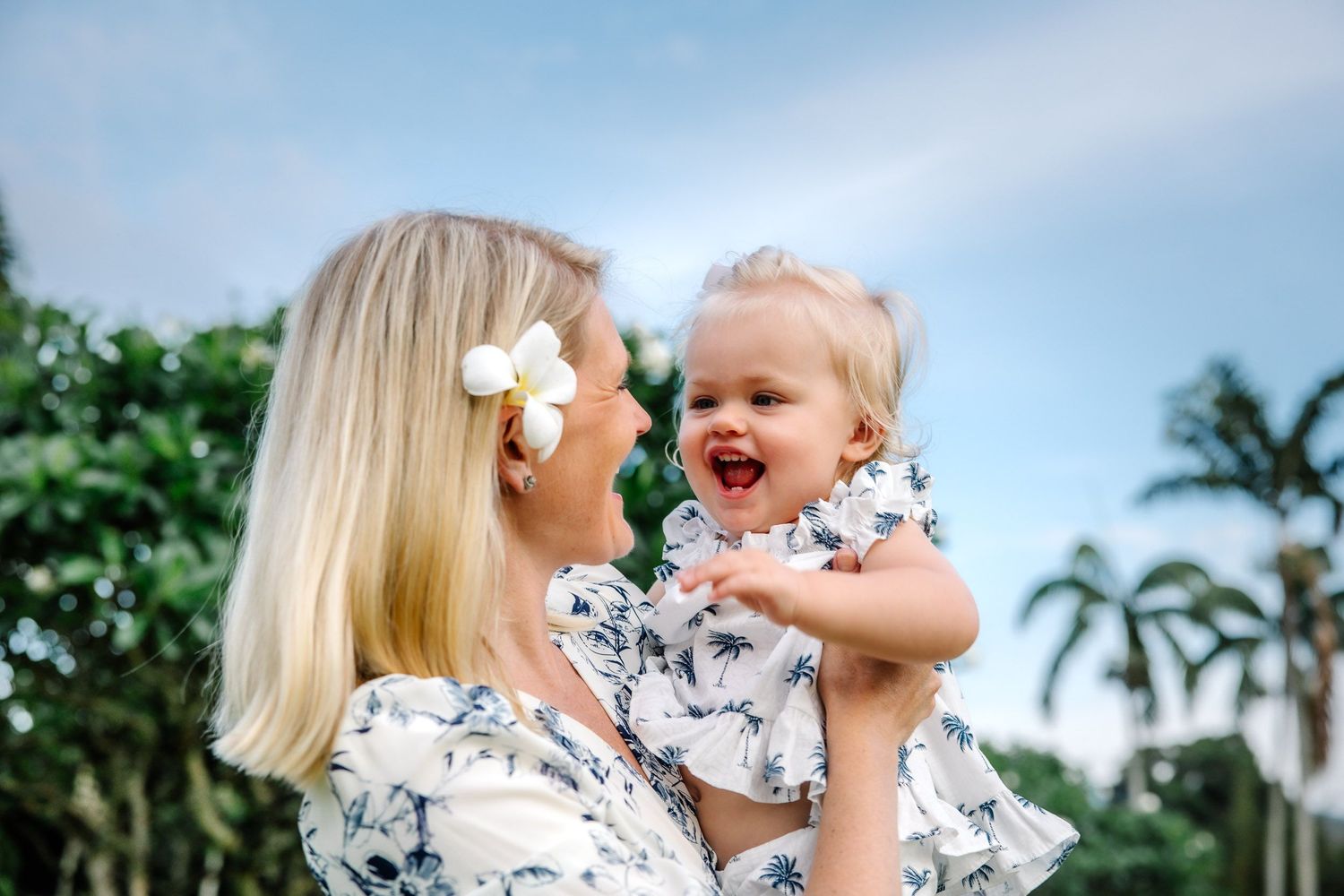 Joyful family moment captured on a sunny beach with palm trees in the background.