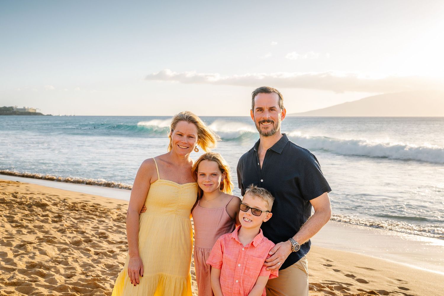 A casual beach photo session with people arranged in front of ocean waves.
