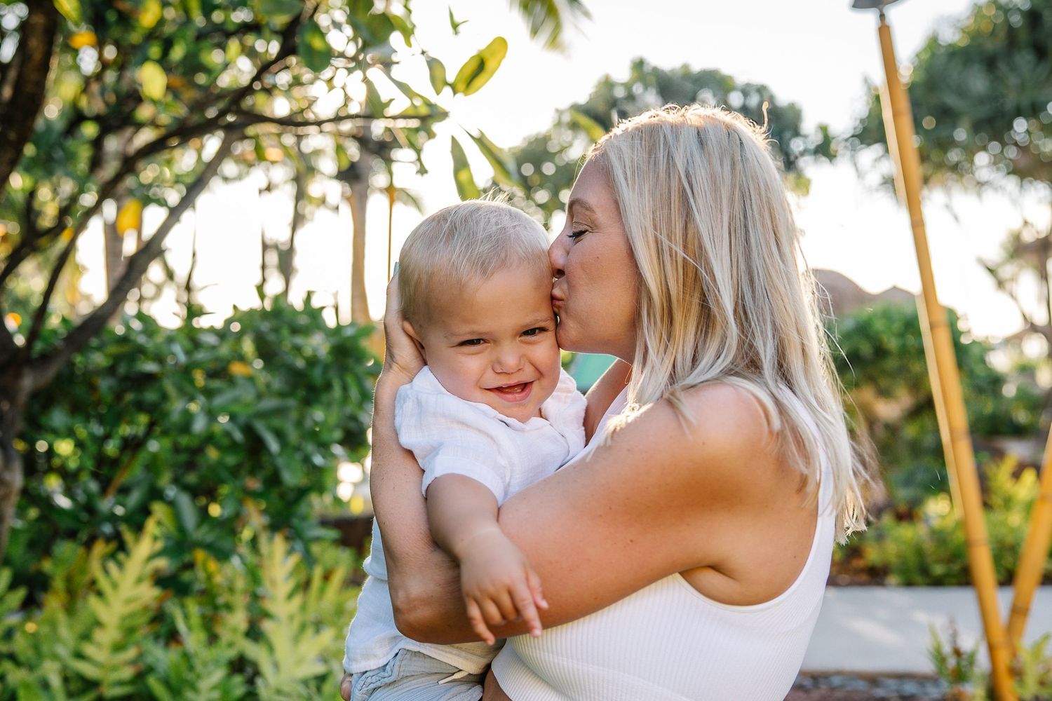 Sweet outdoor family moments captured in golden sunlight among tropical foliage.