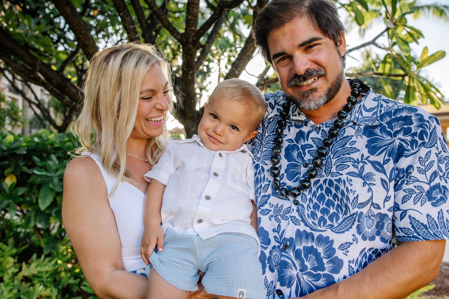 Family photo session in a tropical garden setting with coordinated blue and white outfits.