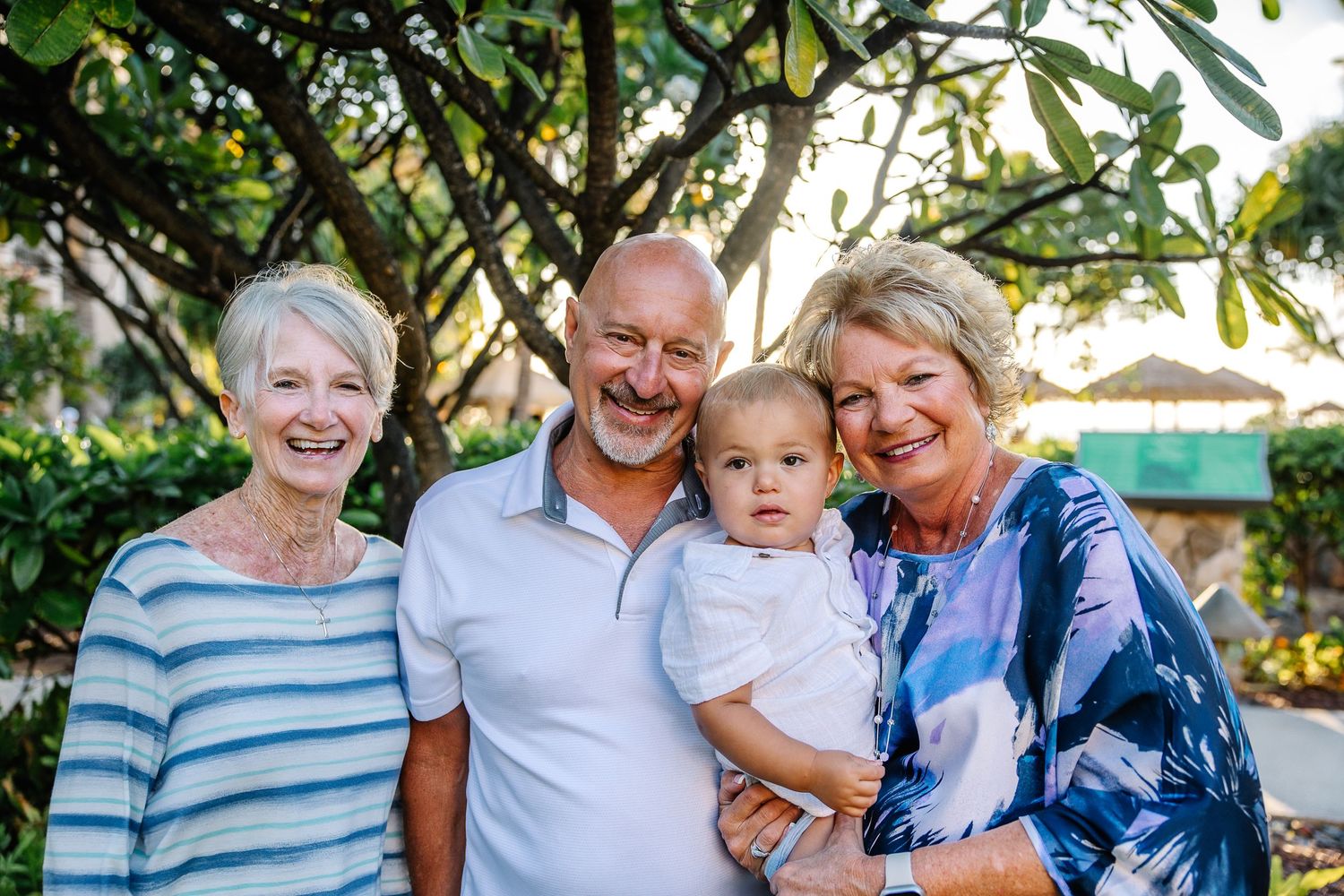 Multi-generational family poses together outdoors in casual attire against a natural backdrop.