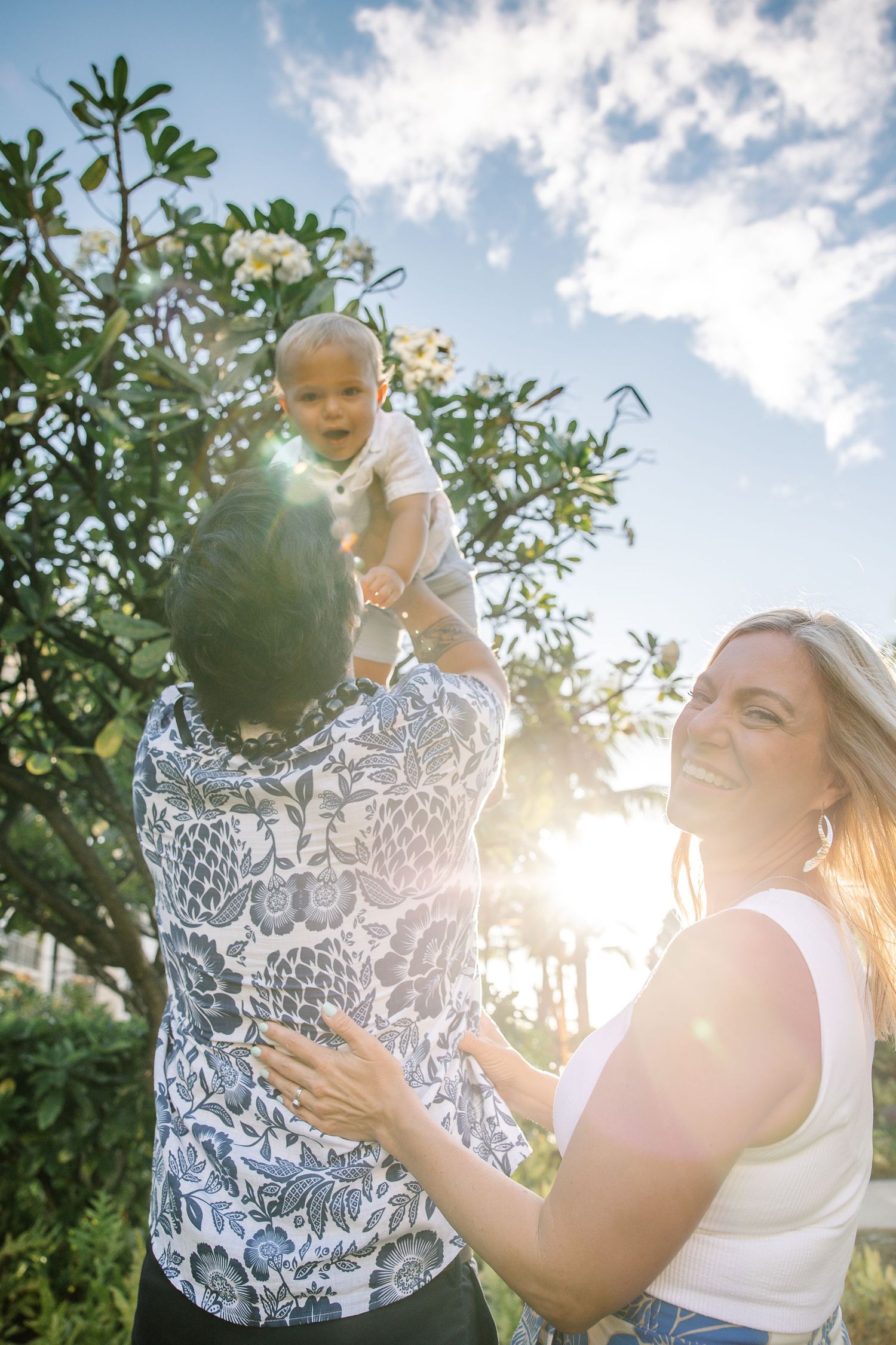 Sunlit outdoor portrait session captures joyful moments between loved ones against blue sky.