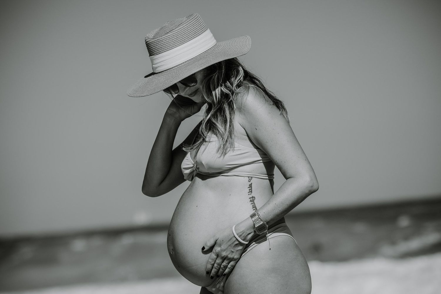 Black and white maternity photo series showing woman's pregnant belly.