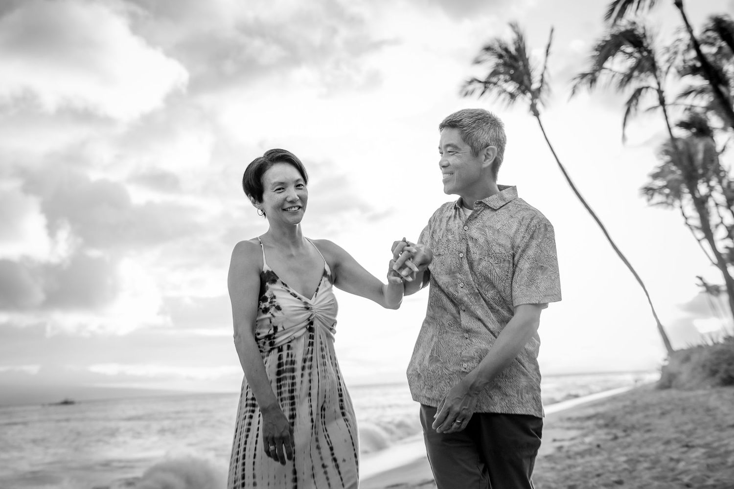 Black and white photo series of a couple enjoying playful moments on a beach with palm trees.