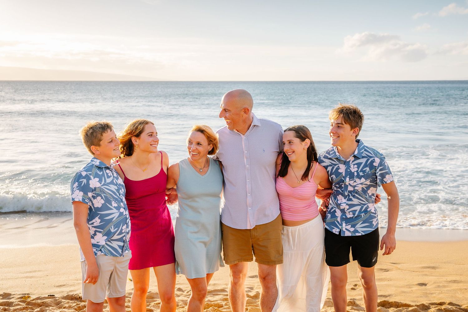 Family members walk together along a beautiful Hawaiian beach during golden hour.