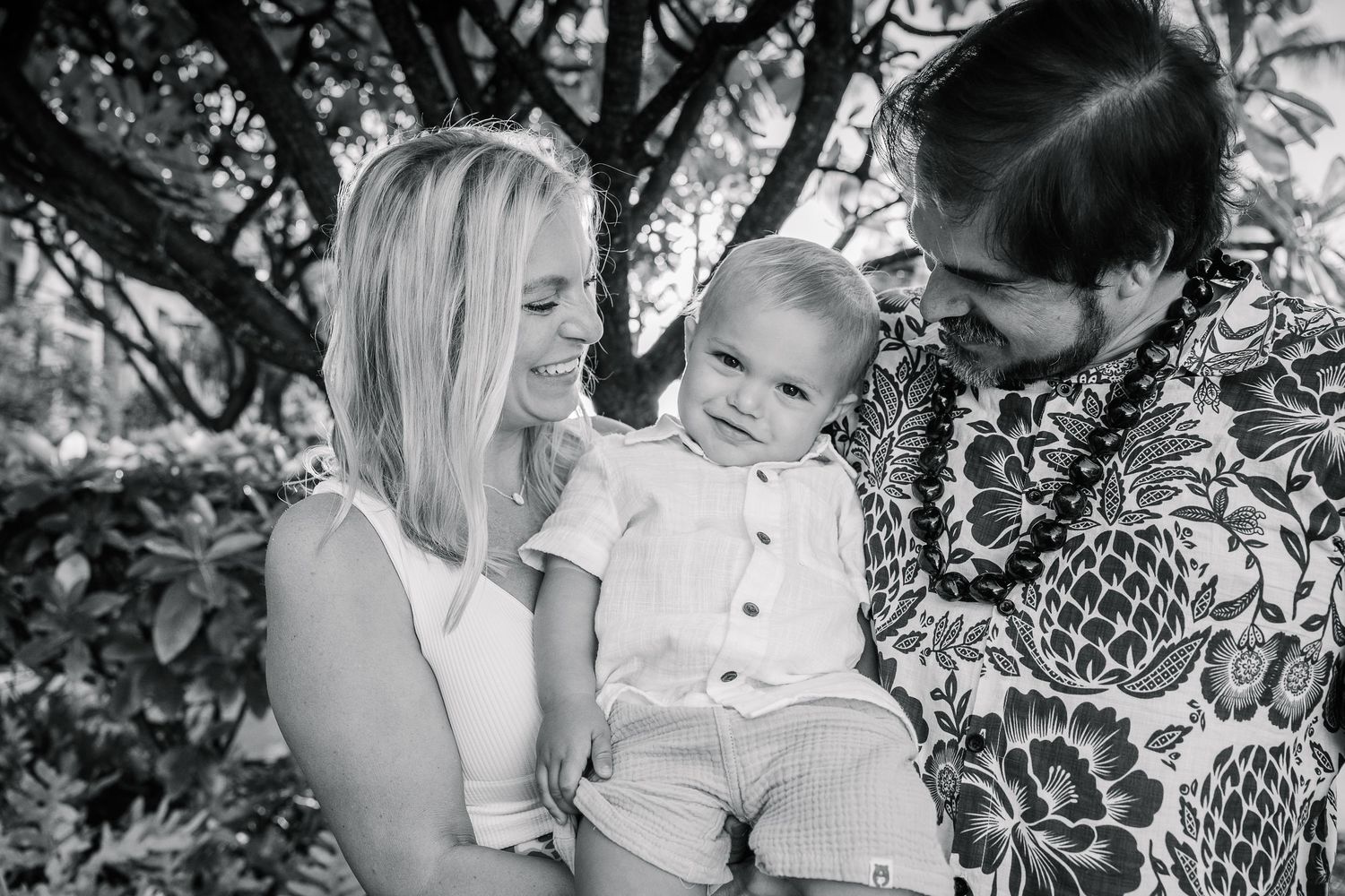 Black and white candid portraits show tender family moments in a natural outdoor setting.