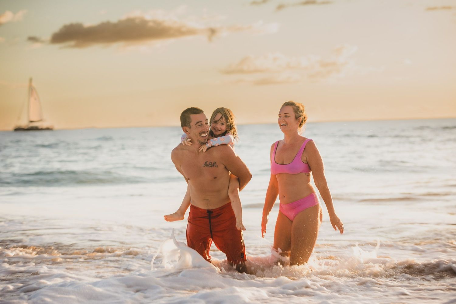 People playing and splashing in ocean waves at sunset on tropical beach.