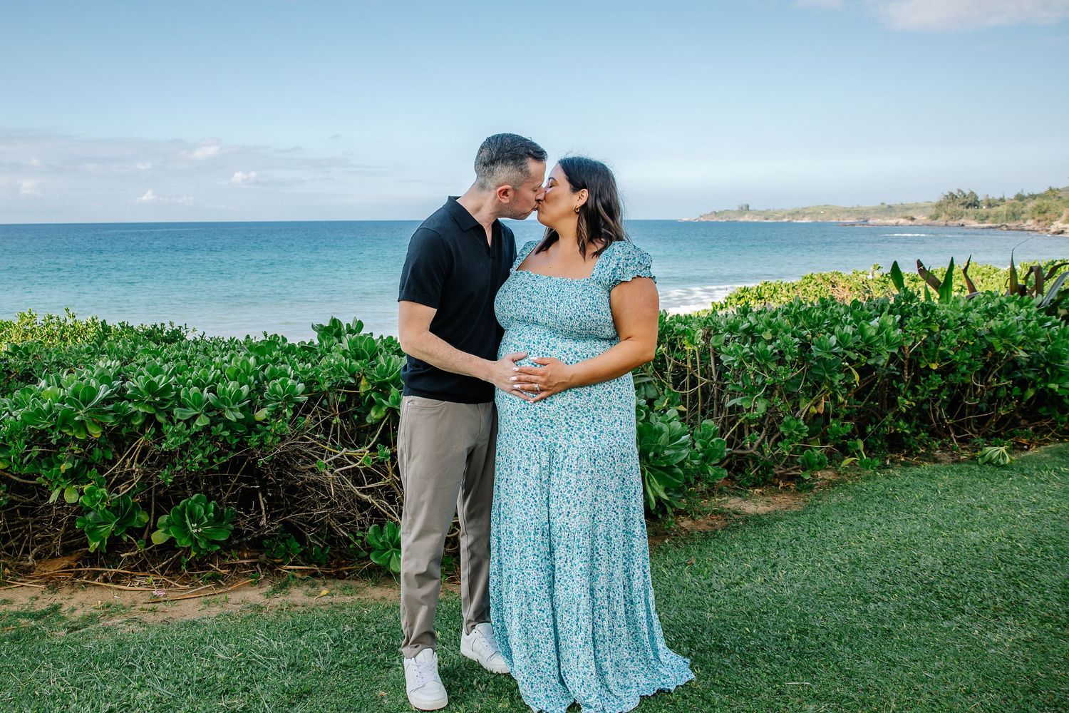 Couple walking along scenic oceanfront path with tropical greenery.