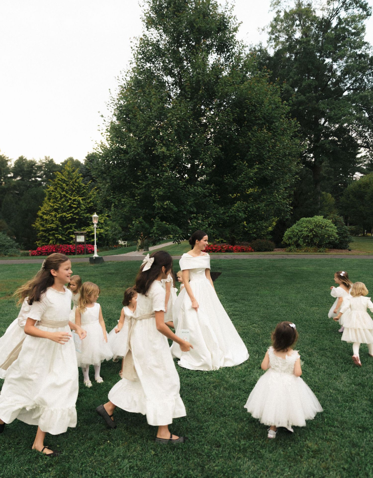 A series of photos showing people in white dresses twirling and dancing joyfully in a grassy field on a sunny day.