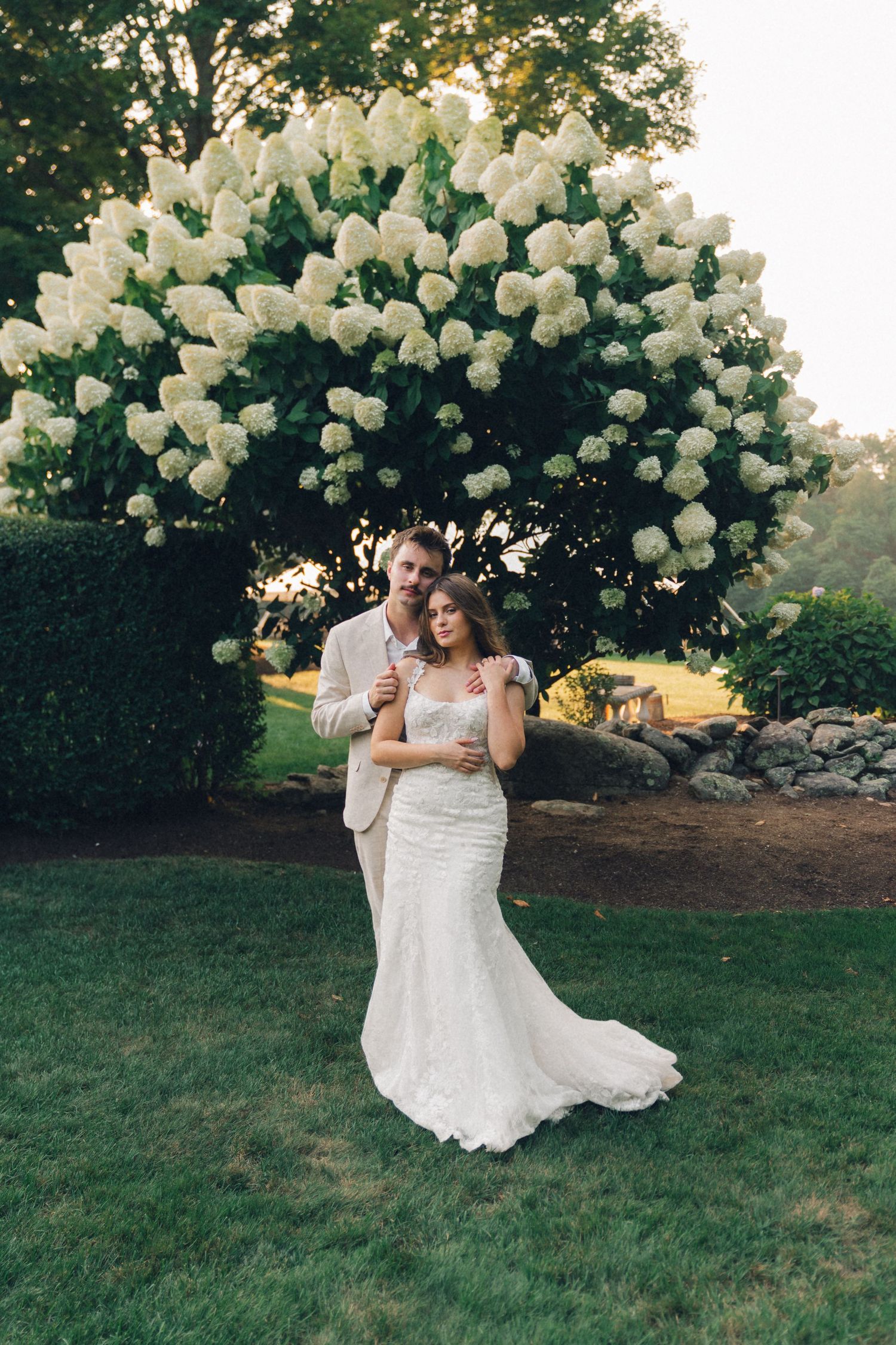 A joyful wedding celebration with white balloons floating in the air against a lush green outdoor backdrop.