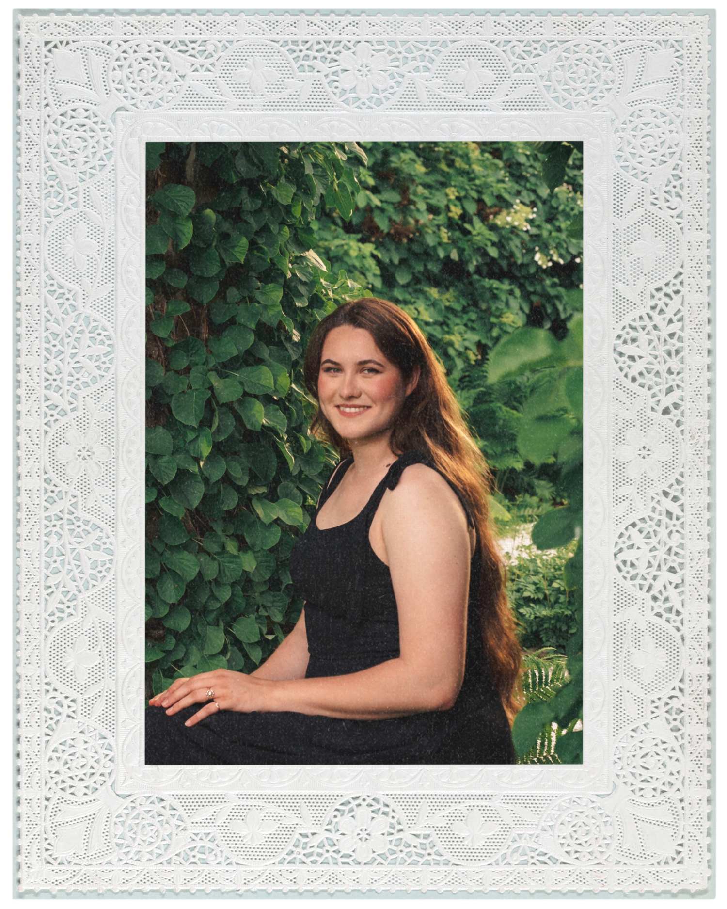 Young woman with long red hair smiling outdoors, framed in an ornate white decorative picture frame.